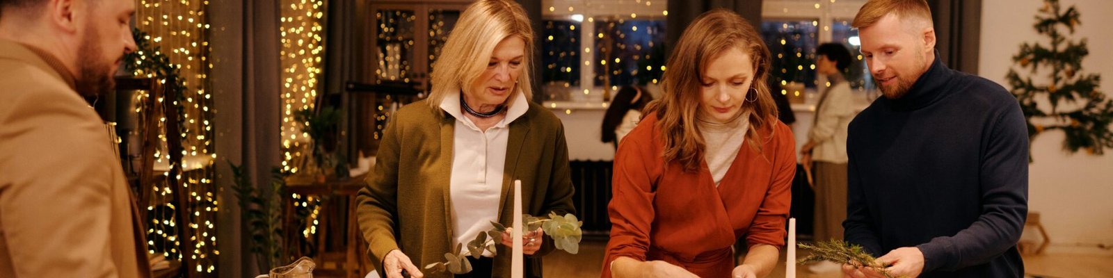 Family setting a festive table for Christmas dinner in a cozy, decorated home.