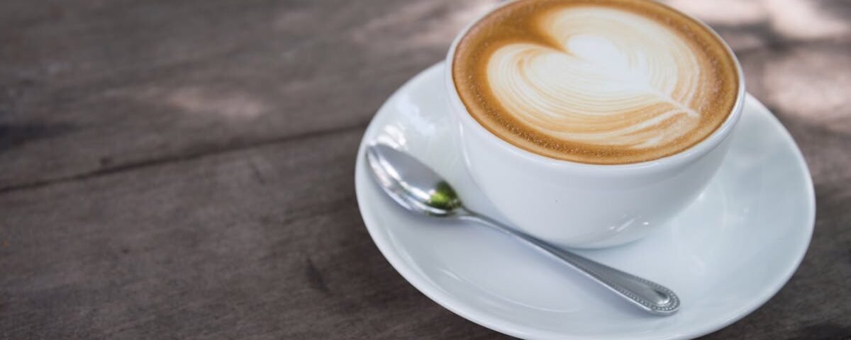 A close-up of a creamy latte with heart latte art on a wooden table, perfect for morning caffeine lovers.