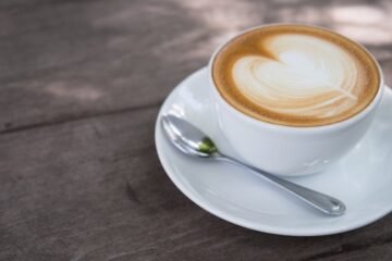 A close-up of a creamy latte with heart latte art on a wooden table, perfect for morning caffeine lovers.