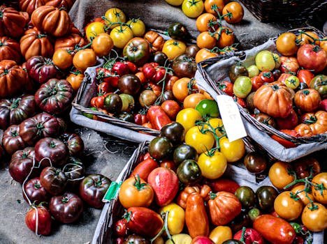 An assortment of fresh, colorful heirloom tomatoes displayed in baskets at an outdoor market, offering a healthy and nutritious option.