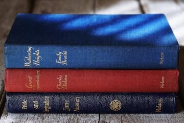 Stacked classics by Brontë, Dickens, and Austen on a wooden surface with dramatic lighting.