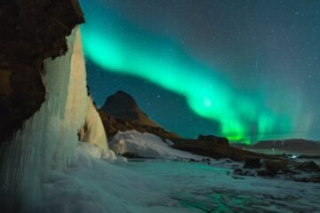 Stunning view of the Northern Lights over Kirkjufell mountain and frozen waterfall in Iceland. Perfect for nature lovers.