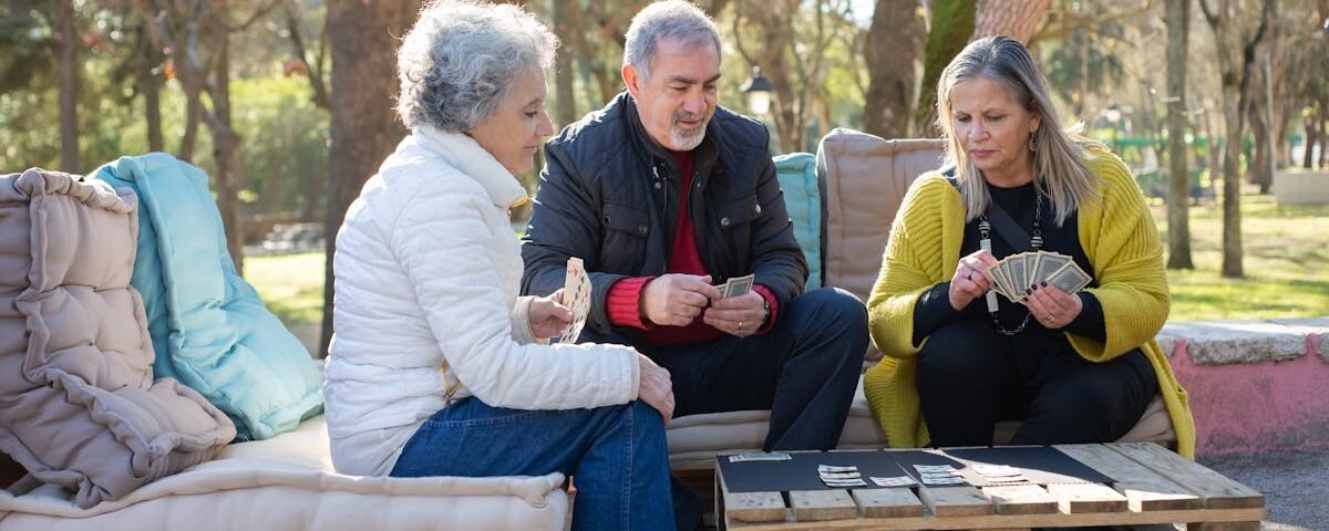 Group of seniors playing cards outdoors, enjoying a relaxing day in Portugal's park.