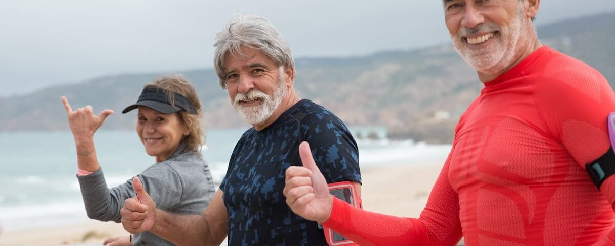 Smiling senior friends exercising on a beach in Portugal, embracing a healthy lifestyle.