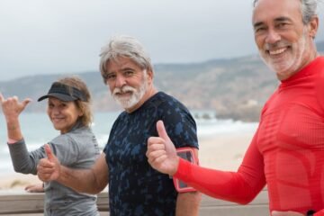 Smiling senior friends exercising on a beach in Portugal, embracing a healthy lifestyle.