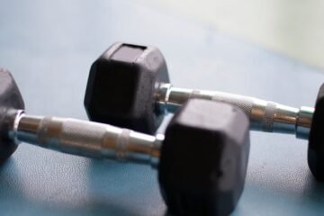 Close-up view of two black hex dumbbells on a gym floor, perfect for fitness content.